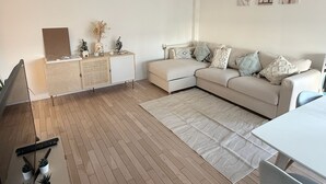 Un soggiorno moderno con un divano, un tavolino, un mobile contenitore e una TV.