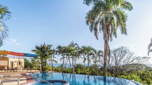 A pool with a hot tub, lounge chairs, and palm trees. - Casa Pura Vida (Sámara)