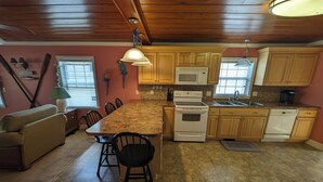 Una cocina con armarios de madera, encimera de granito, estufa blanca y un comedor con mesa y sillas.