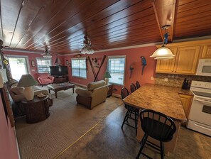 A spacious living area with a wooden ceiling, a dining table, and a kitchen with wooden cabinets. - Cute Beachy Bungalow-walking distance to beach-3 bd/2 ba house in NMB (North Myrtle Beach)