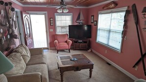 Una sala de estar con sofá, sillón, mesa de centro, televisor y una decoración náutica de velero.