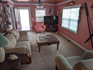 A living room with a sofa, armchair, coffee table, television, and a sailboat decoration. - Cute Beachy Bungalow-walking distance to beach-3 bd/2 ba house in NMB (North Myrtle Beach)