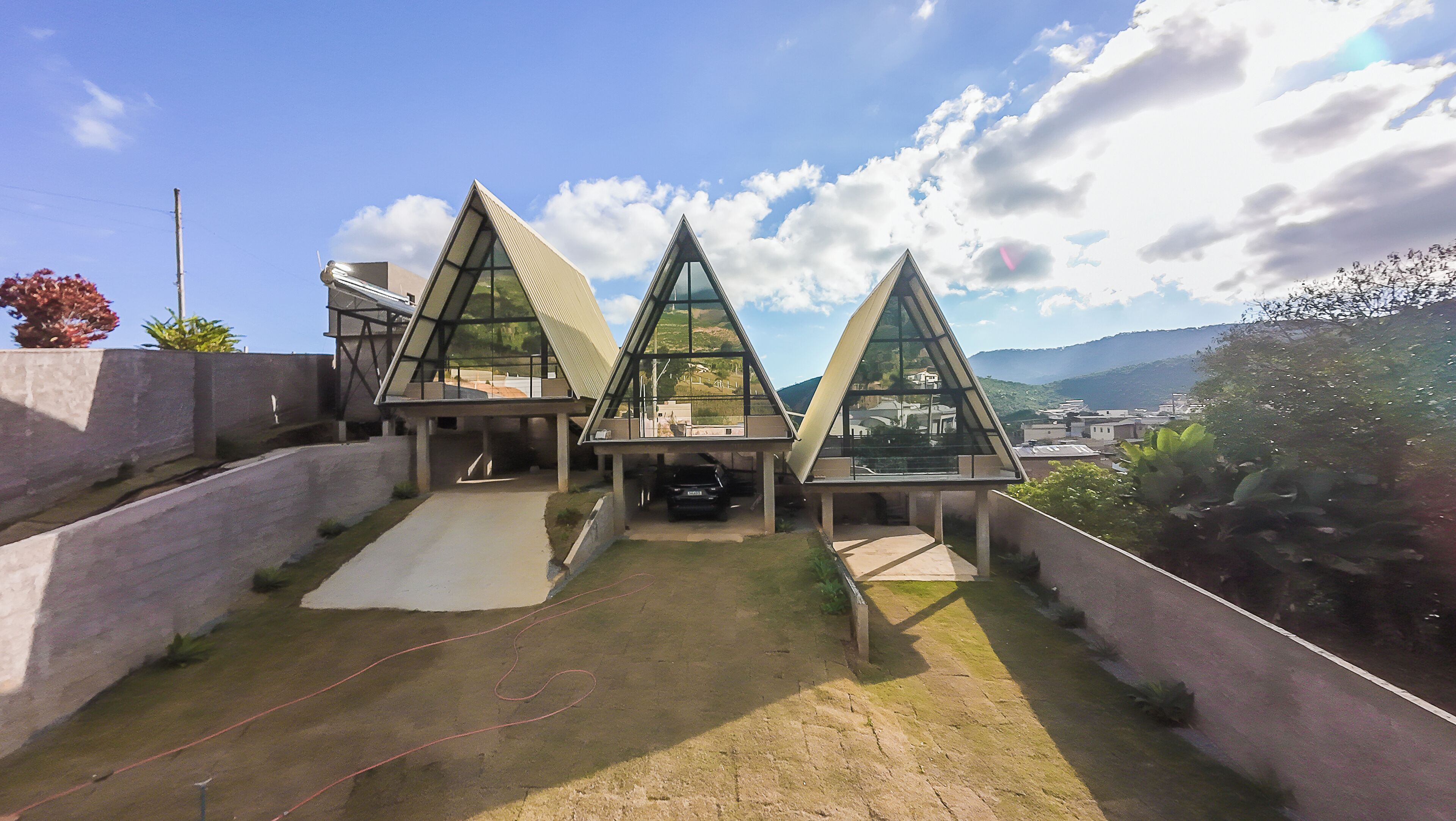 A modern building with a triangular roof design, a paved entrance area, and a view of the surrounding landscape.
