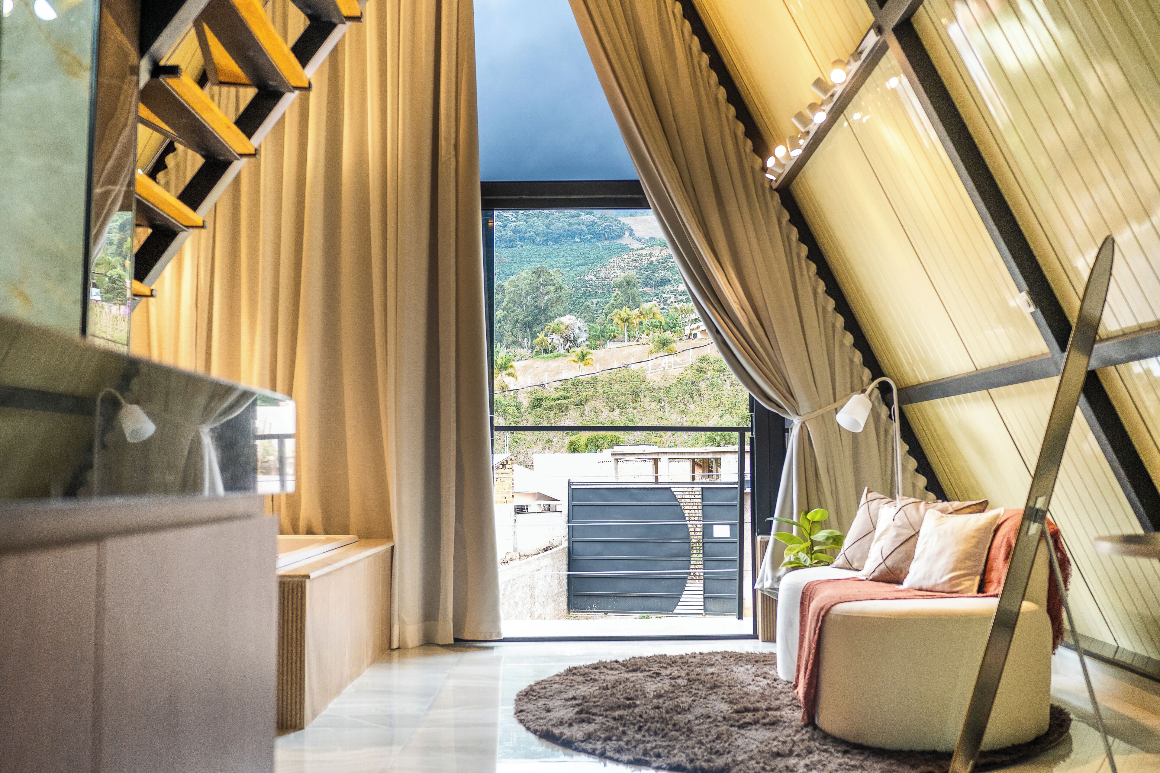 Ein modernes Interieur mit Balkon, einer Sitzecke und Blick auf eine hügelige Landschaft.