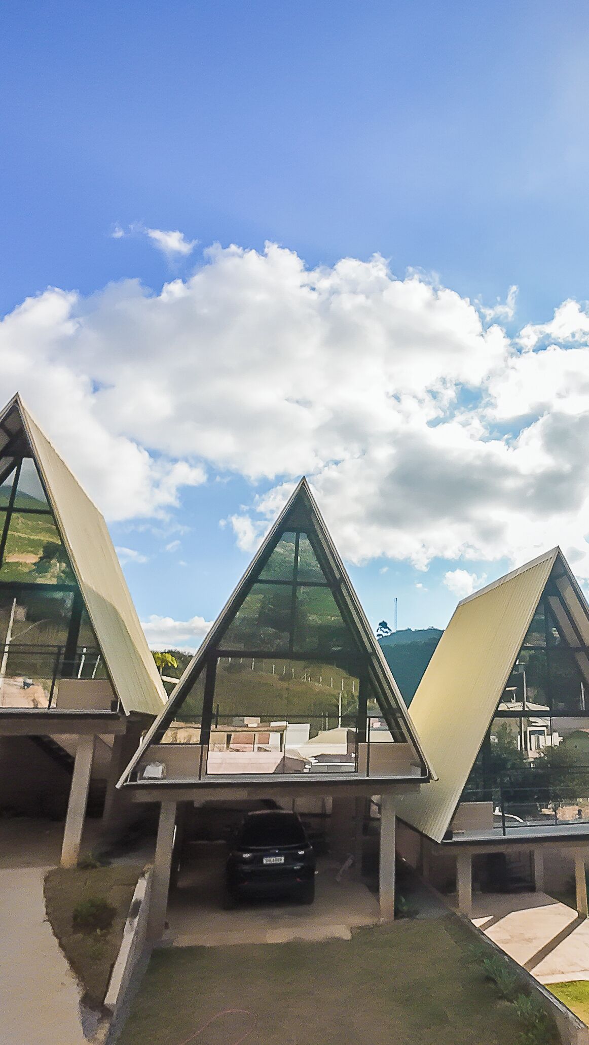 Un bâtiment moderne doté d’une façade triangulaire en verre et d’un espace de stationnement à l’avant.