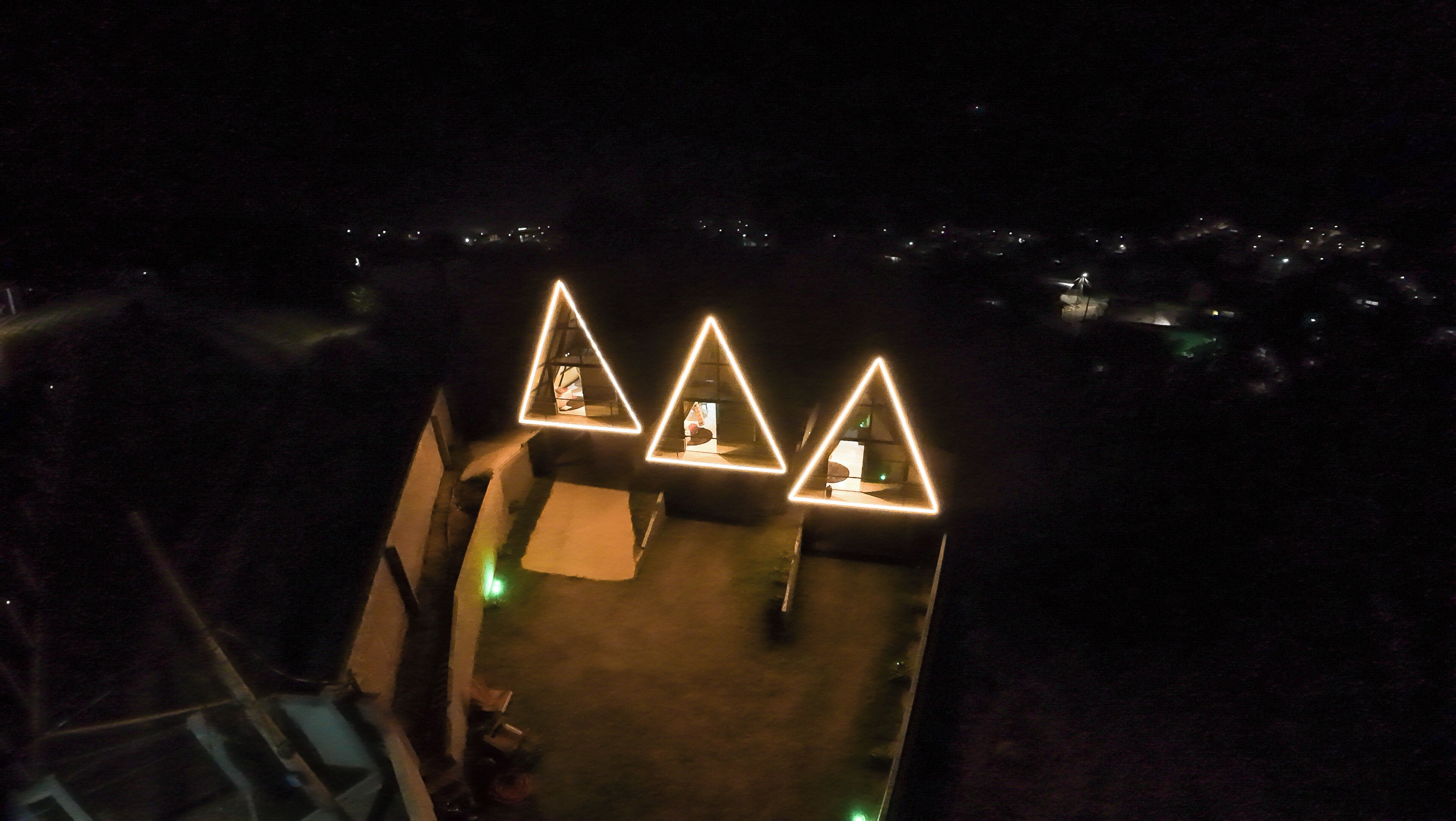 Een dak met drie verlichte, driehoekige constructies, mogelijk voor evenementen of decoratie.
