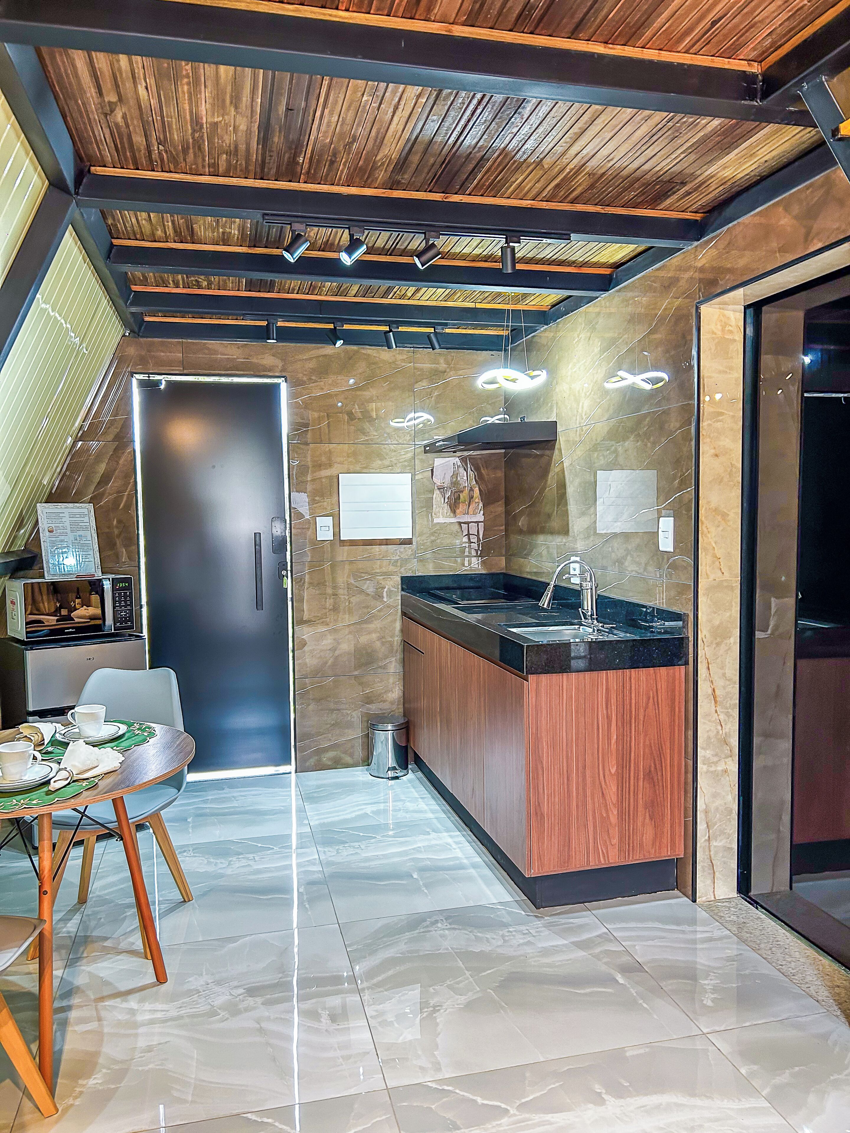 A modern kitchen with a wooden ceiling, a marble countertop, and a dining area with a table and chairs.