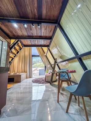 A modern interior with a sloped ceiling, a dining area with a table and chairs, and a view of the outdoors.