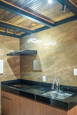 A modern kitchen with a black countertop, stainless steel sink, and wooden cabinets.