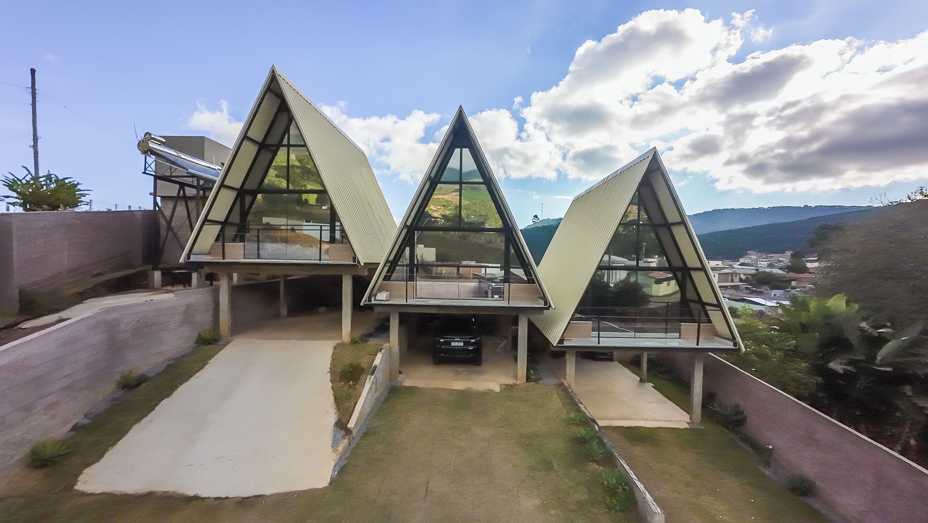 Een modern huis met een opvallend driehoeks ontwerp, een oprit en een auto in de garage.