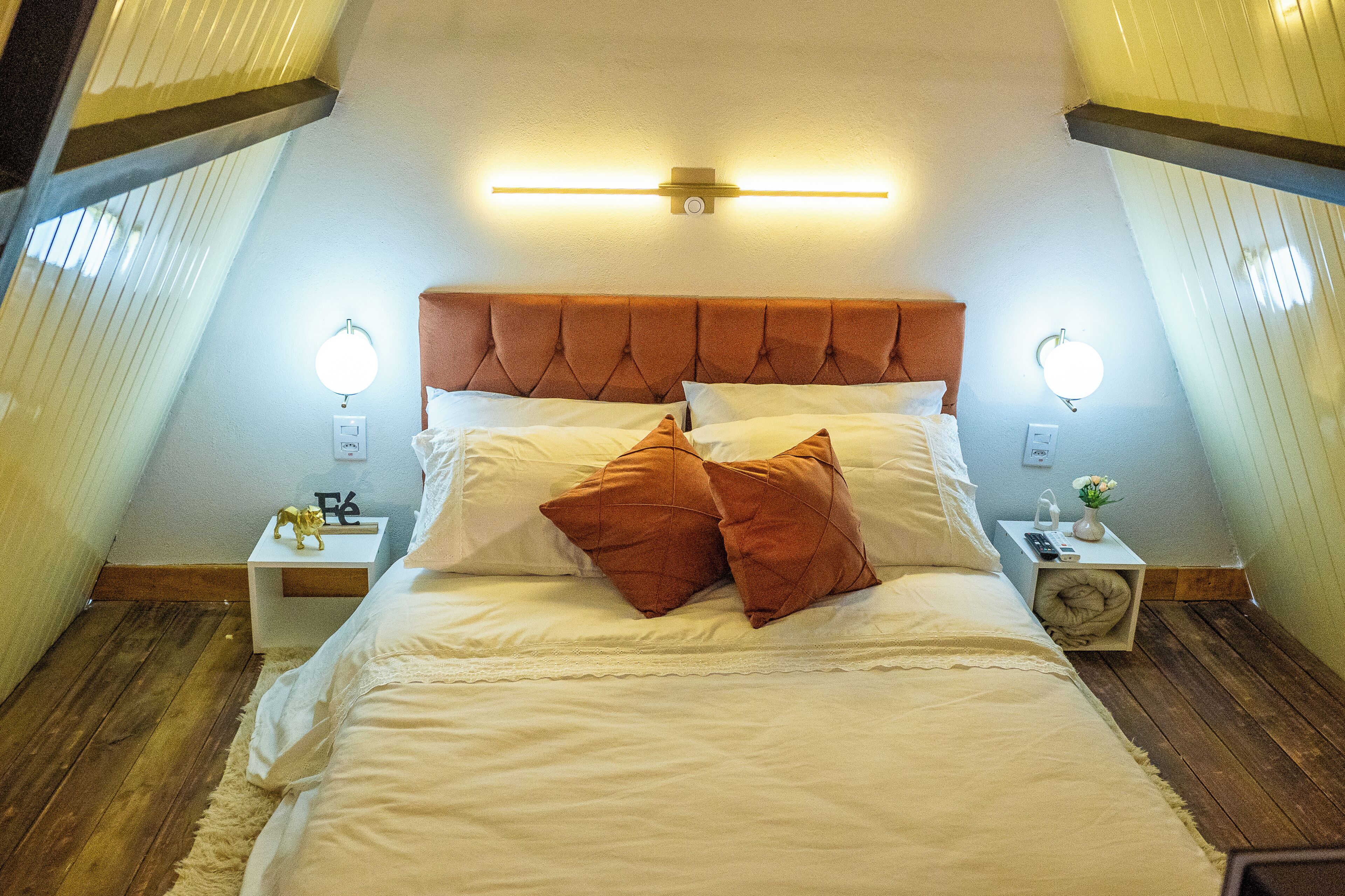 Une chambre à coucher avec un grand lit, deux tables de chevet et un luminaire fixé au mur.
