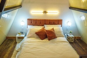 A bedroom with a large bed, two bedside tables, and a wall-mounted light fixture.