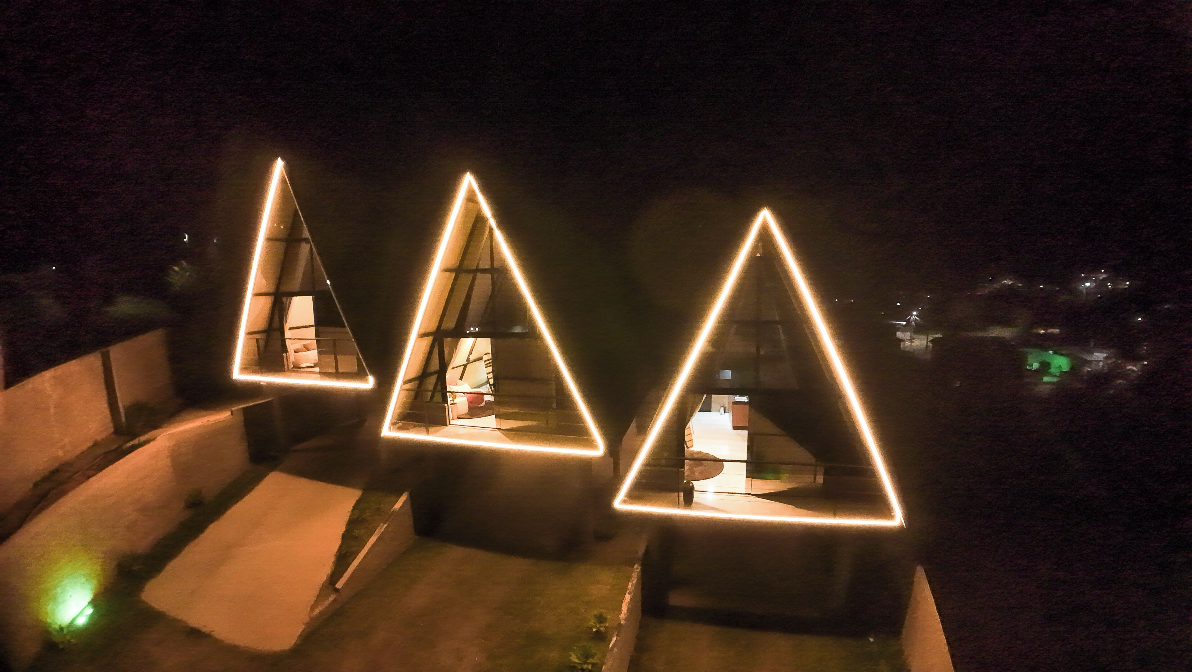 Three triangular structures with illuminated outlines, possibly part of a hotel or resort.