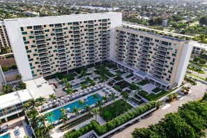 Un hotel moderno con numerosi balconi, una piscina e un cortile curato.