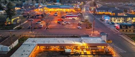 Une station-service avec un parking, un motel et une autoroute en arrière-plan.