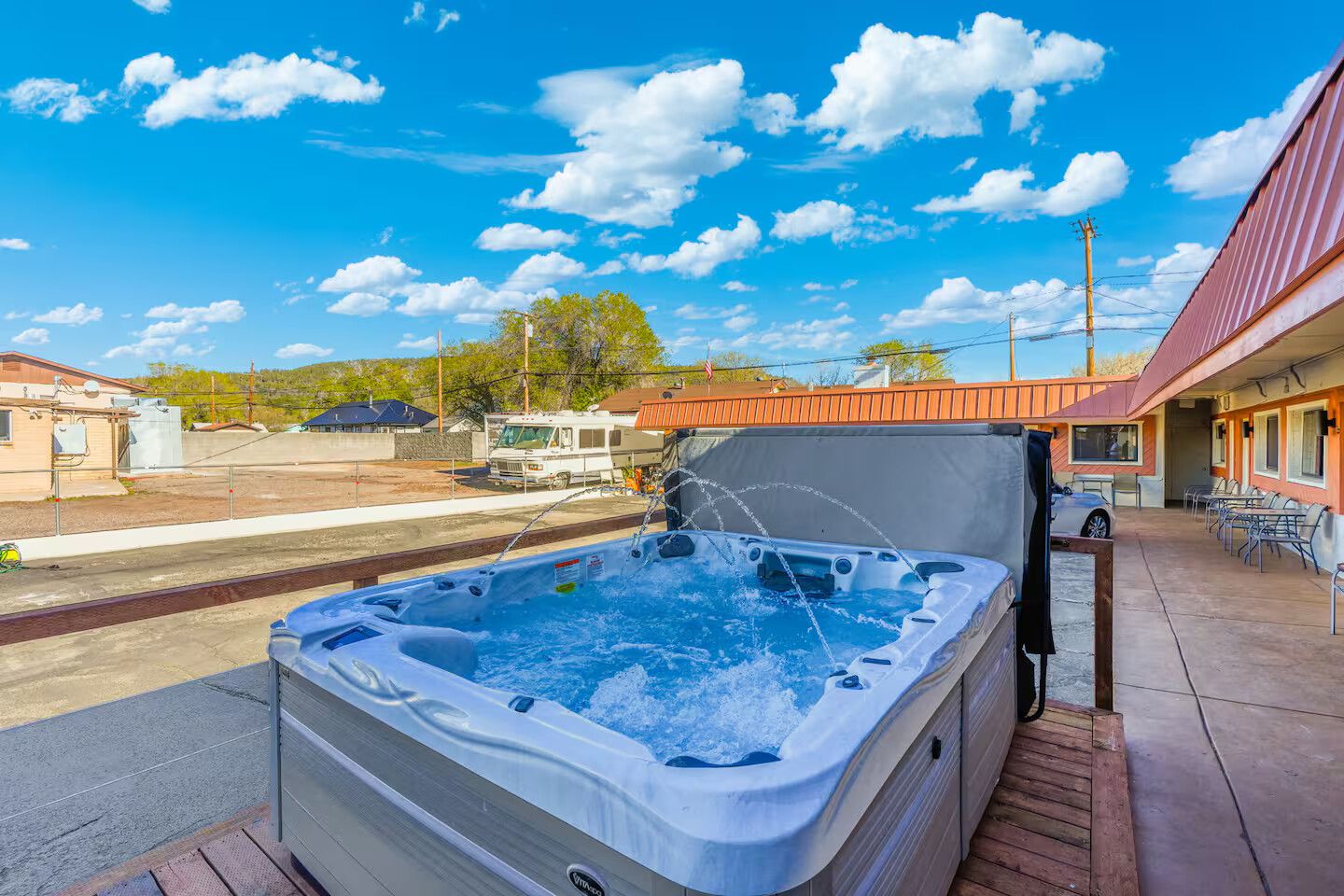 A hot tub on a patio with a clear sky and a building in the background.