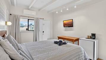 A bedroom with a bed, a desk, a coffee machine, and a TV.