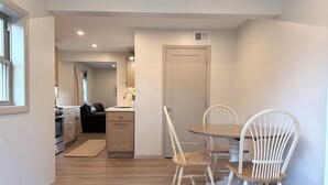 Une cuisine moderne avec un coin repas, un plancher en bois et une vue sur le salon.