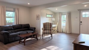 Un salon avec un canapé, une table basse en bois, un fauteuil à rayures et une lampe.