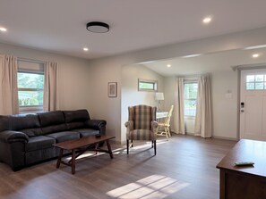 Una sala de estar con un sofá, una mesa de centro de madera, un sillón a rayas y una lámpara.