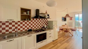 A compact kitchen with a checkered backsplash, a dining area with a table and chairs, and a view of the outdoors. - 2-bedroom apartment in tranquil Brenzone sul Garda with AC (Brenzone sul Garda)