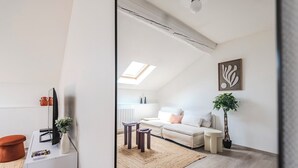 A modern living room with a sofa, a coffee table, a rug, and a plant. - Le Grandval - Spacious 3 rooms (Reims)