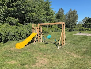 A playground with a yellow slide and swings.