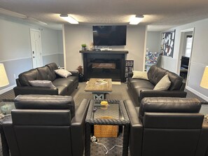 A living room with two leather sofas, a coffee table, and a flat-screen TV above a fireplace. - Welcome to Wellington Manor Condo, a cozy studio vacation rental in Wells, Maine, perfectly located near Wells Beach, local restaurants, shopping, and popular Southern Maine coastal attractions. This comfortable Wells studio condo is ideal for couple (Wells)