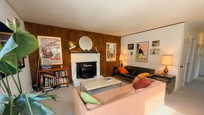 Een woonkamer met een open haard, een bank, een salontafel, een boekenkast en een lamp.