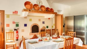 Comedor con una mesa dispuesta para cuatro, un extintor de incendios y un refrigerador moderno de acero inoxidable.