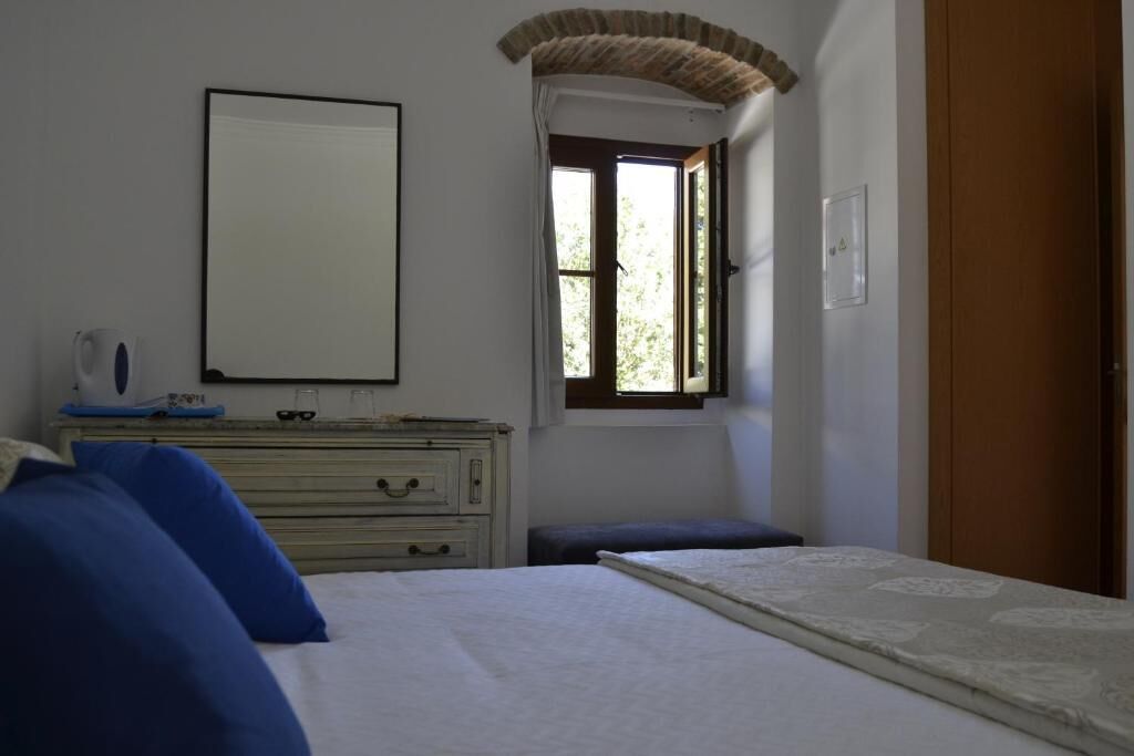 Un dormitori amb un llit, un prestatge, una finestra amb cortines i una porta.