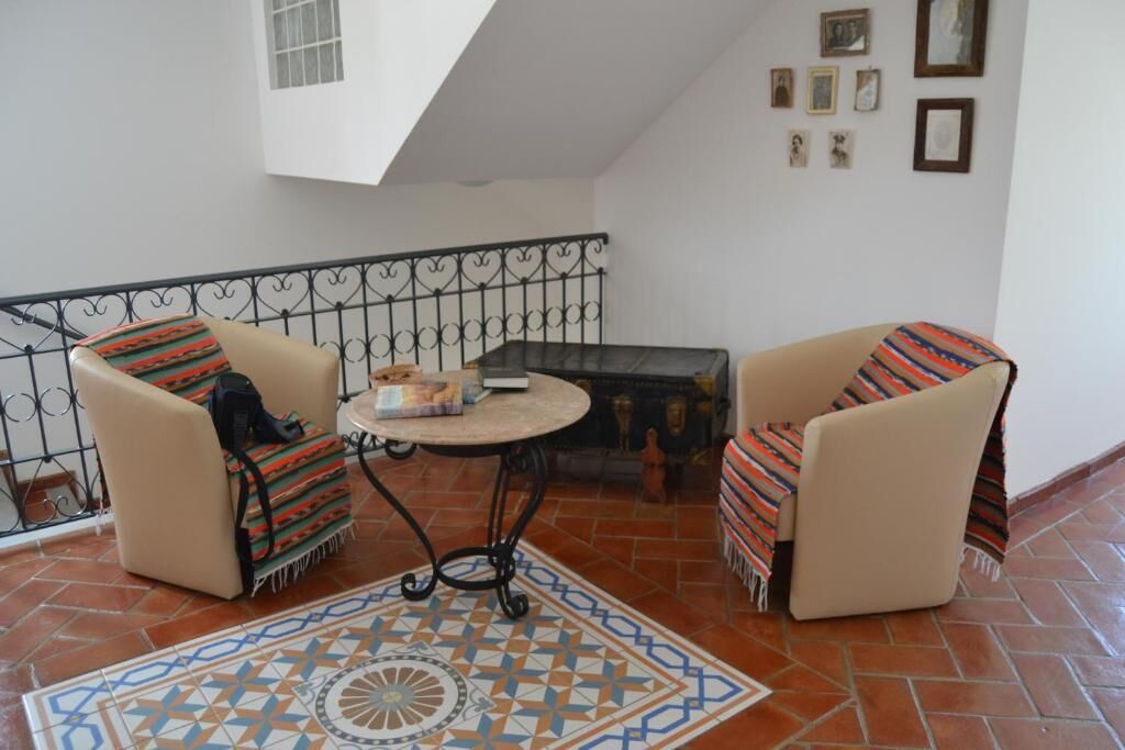 Un balcon avec deux chaises, une petite table et un tapis décoratif.