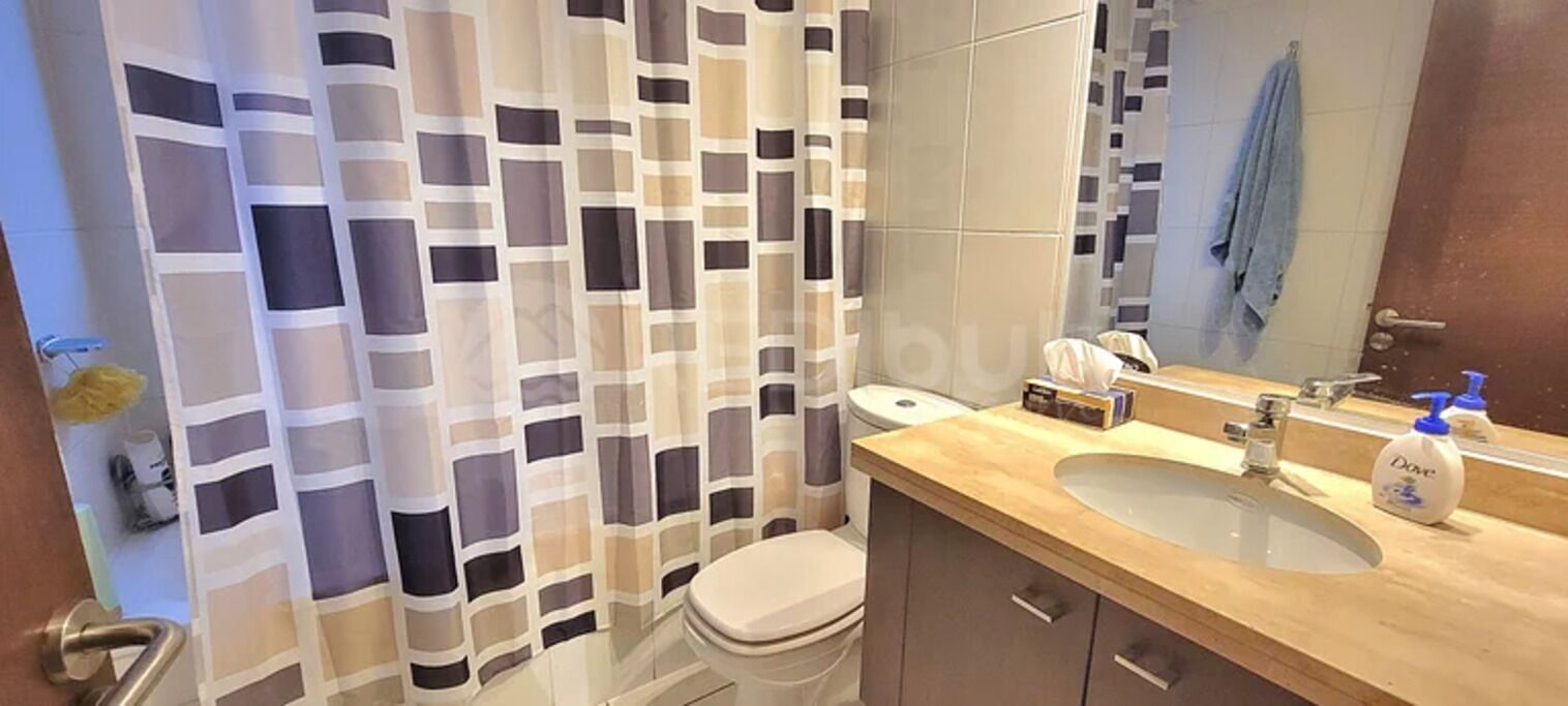 A bathroom with a shower curtain, toilet, sink, and mirror.