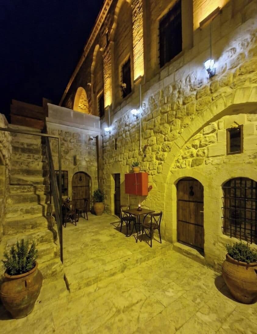 A stone building with a courtyard, wooden doors, and potted plants.