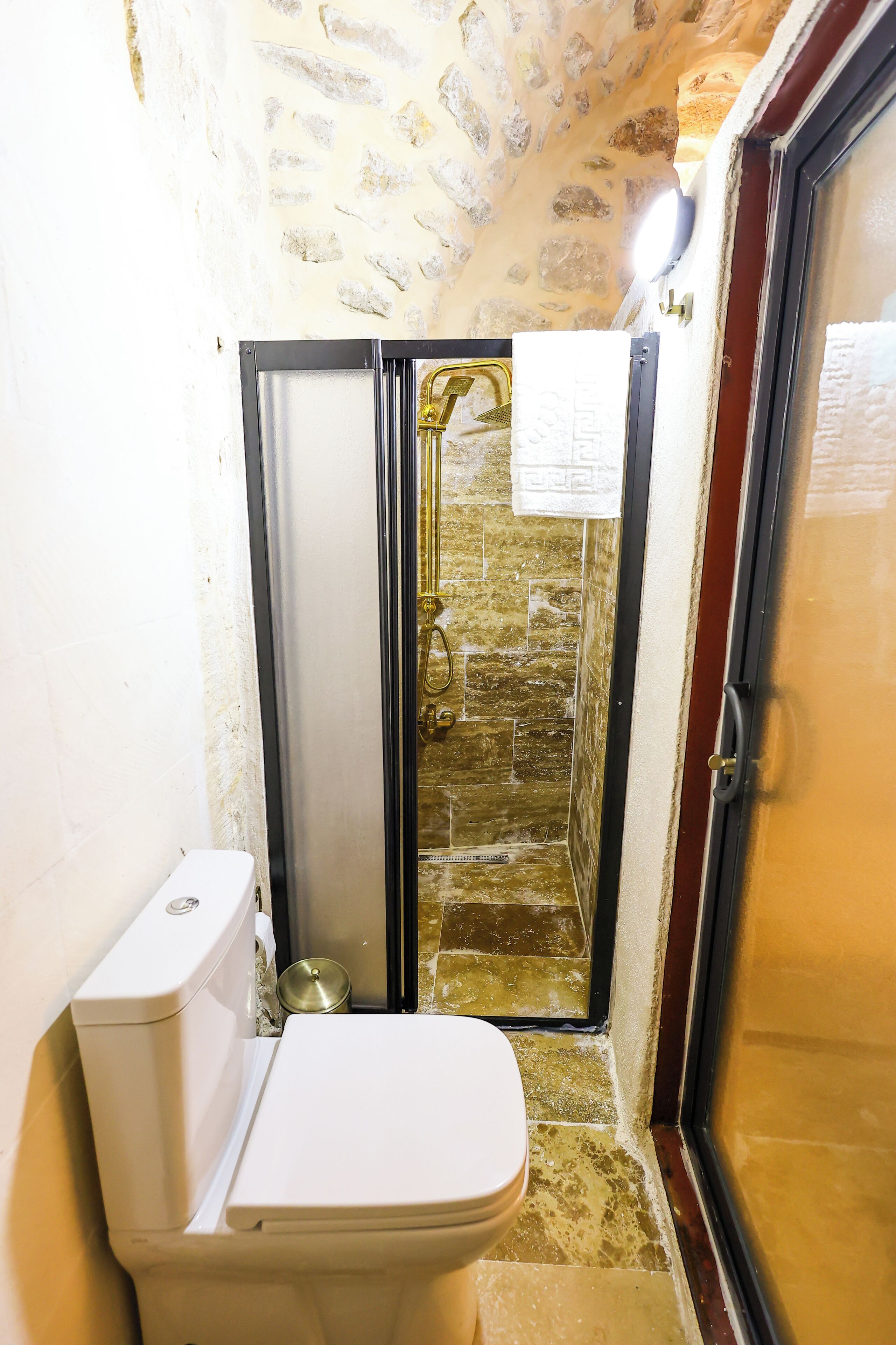 Un baño con inodoro, cabina de ducha y puerta de vidrio.