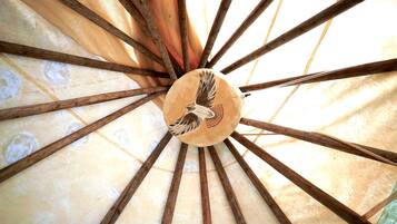 A ceiling with a wooden beam structure and a central circular element with a bird design.
