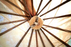 A ceiling with a wooden beam structure and a central circular element with a bird design.