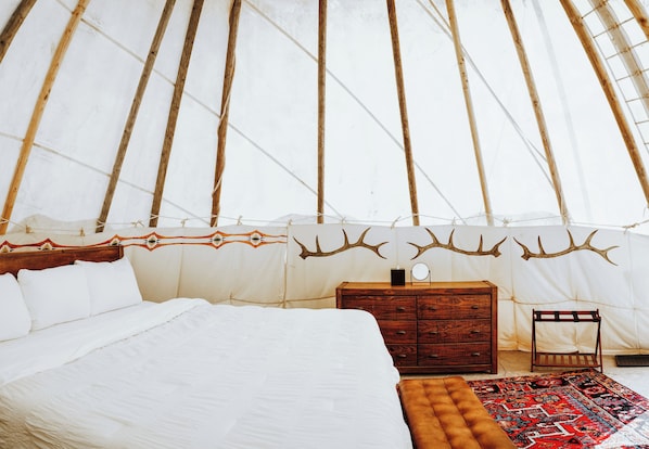 A spacious room with a large bed, a wooden dresser, and a patterned rug.