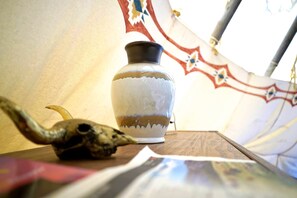 A tent interior with a decorative vase and a skull on a table.