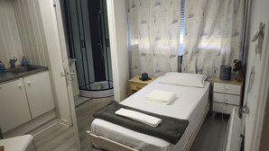 A bedroom with a bed, a bedside table, a nightstand, a shower, and a bathroom. - Stay in Dunkirk: Room Near Malo Beach and Shops (Dunkerque)