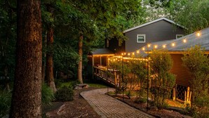 Een huis met een overdekt terras, een tegelpad en lichtjes.