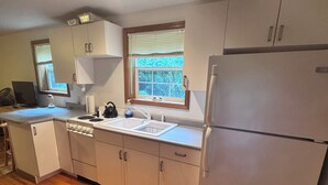 A kitchen with a refrigerator, sink, and window.