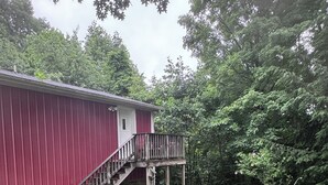 A red building with a wooden deck and stairs leading to a door.