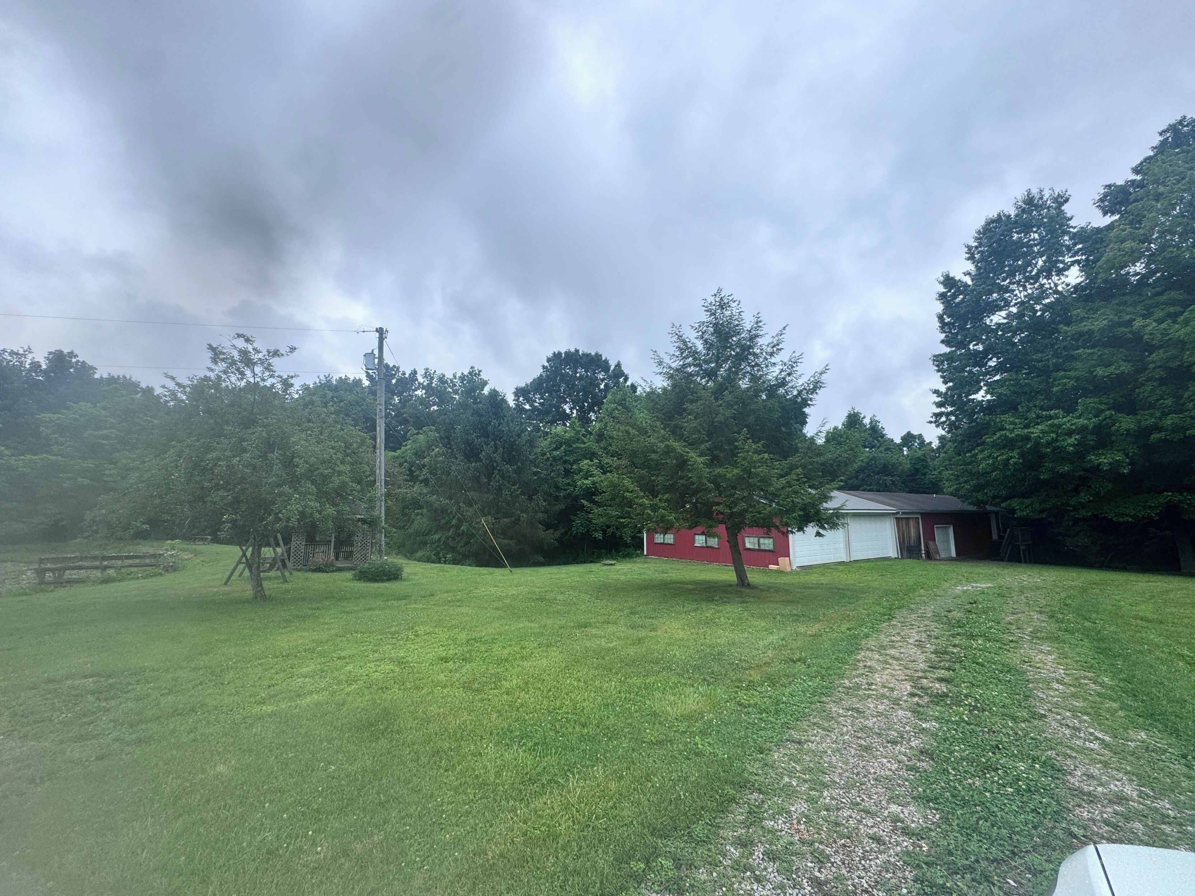 A grassy yard with a red building, a wooden fence, and a utility pole.