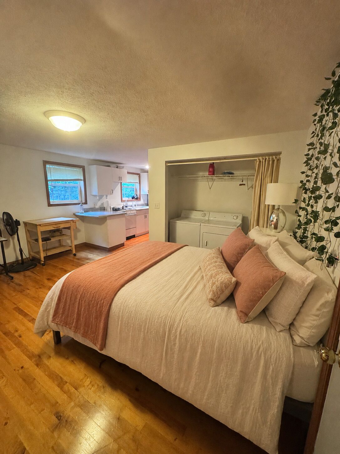 Ein Schlafzimmer mit Bett, Schreibtisch, Waschmaschine und Blick ins Freie.