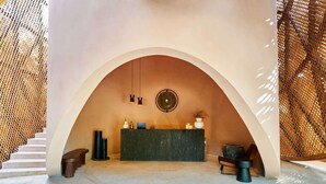 A reception area with a reception desk, two chairs, a wall-mounted circular decoration, and a staircase. - Luxury 1BR Aflora Retreat in Aldea Zama with  pool (Tulum)