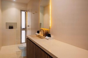 Un bany modern amb un mirall gran, un lavabo i un vàter.
