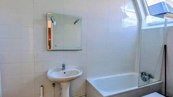 Un baño con lavabo, espejo y bañera.
