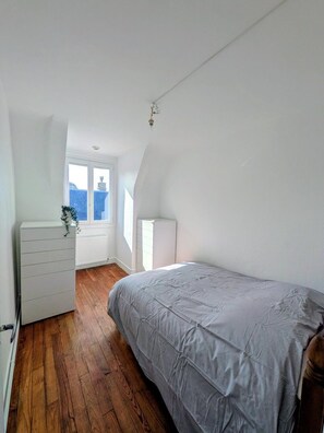 A bedroom with a bed, dresser, radiator, and a window with a view. - right by the sea (Saint-Valery-en-Caux)