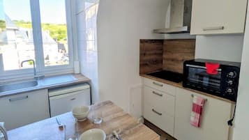 Una cocina compacta con ventana, microondas y piso a cuadros.
